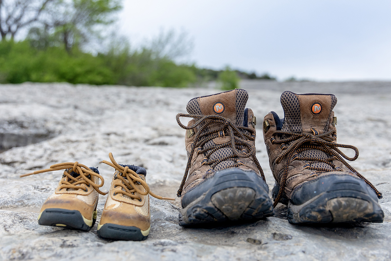 baby and adult hiking shoes next to each other on a trail