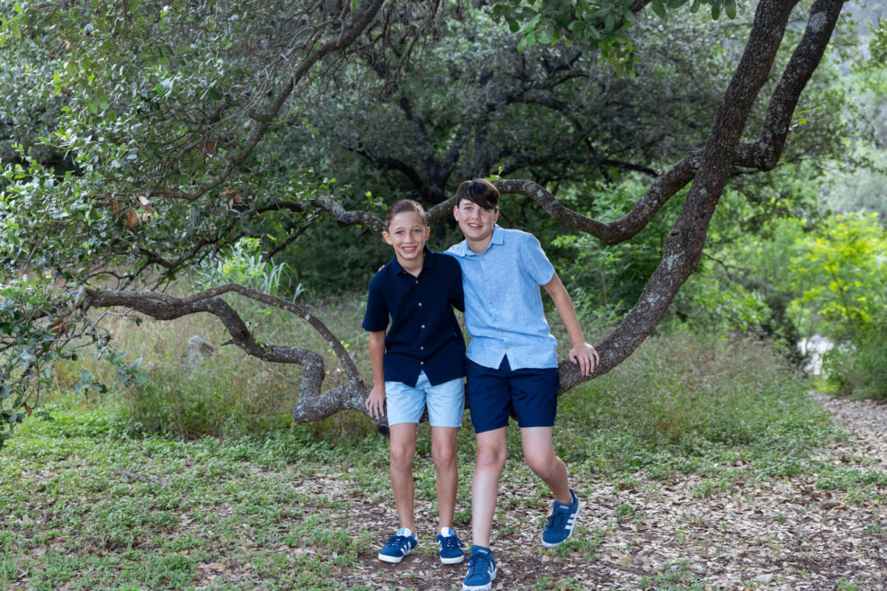 brothers on tree branch during family photo session in austin park