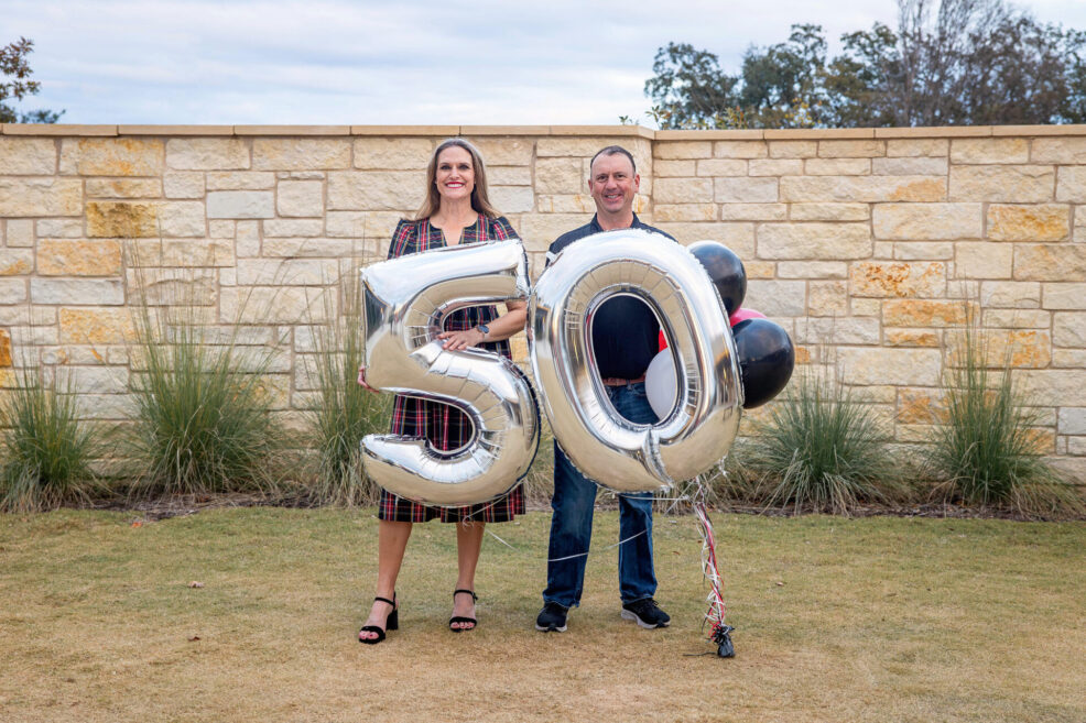 couple holding number 50 balloons